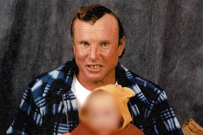 A man with short hair and a blue checkered shirt looks at the camera