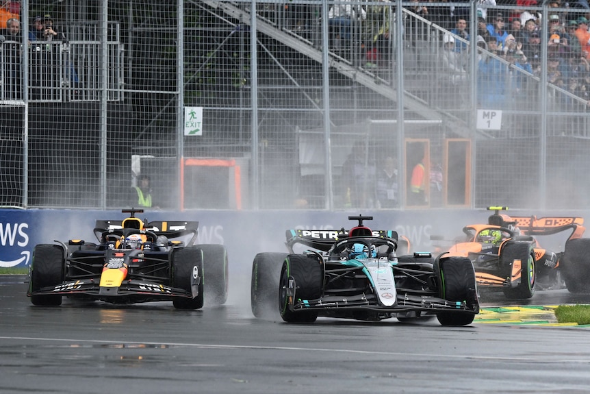 In the rain, a Mercedes car leads the Red Bull, with spray rising from wheels