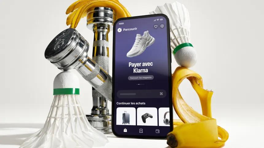 Standing phone with Klarna app open in front of workout gear