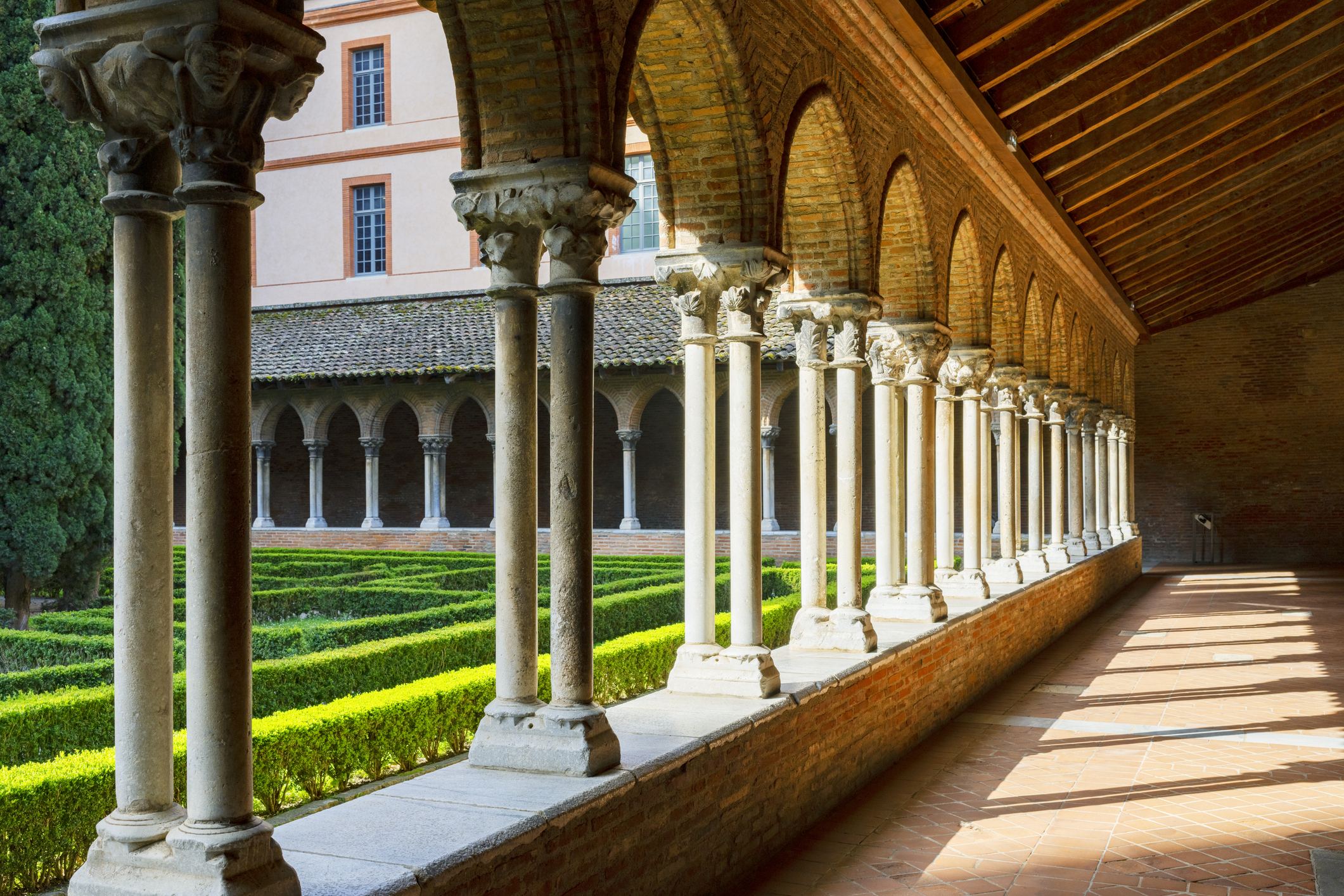 A series of cloisters - an arched covered walkway - goes around a manicured courtyard garden 