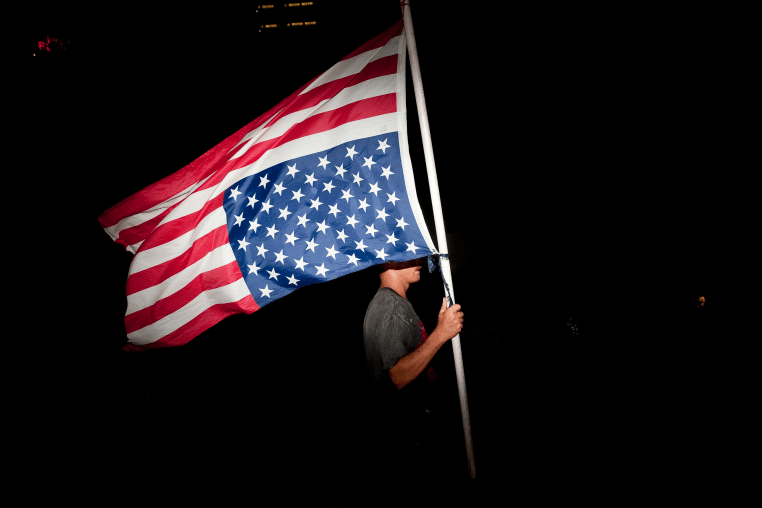A protester with an upside-down American flag 