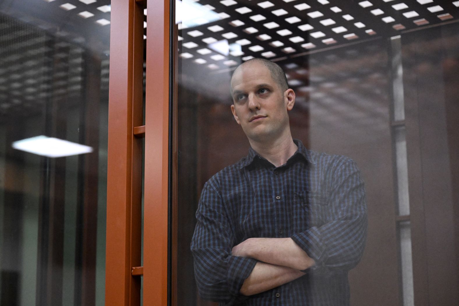 Evan Gershkovich, the first American journalist to be arrested on espionage charges in Russia since the Cold War, looks out from inside a courtroom’s glass cage before <a href="https://www.cnn.com/2024/06/26/europe/evan-gershkovich-trial-begin-russia-intl/index.html">a hearing</a> in Yekaterinburg, Russia, on Wednesday, June 26. Gershkovich has been detained in Russia for over a year. The US government and his employer, the Wall Street Journal, have vehemently denied the charges against him.