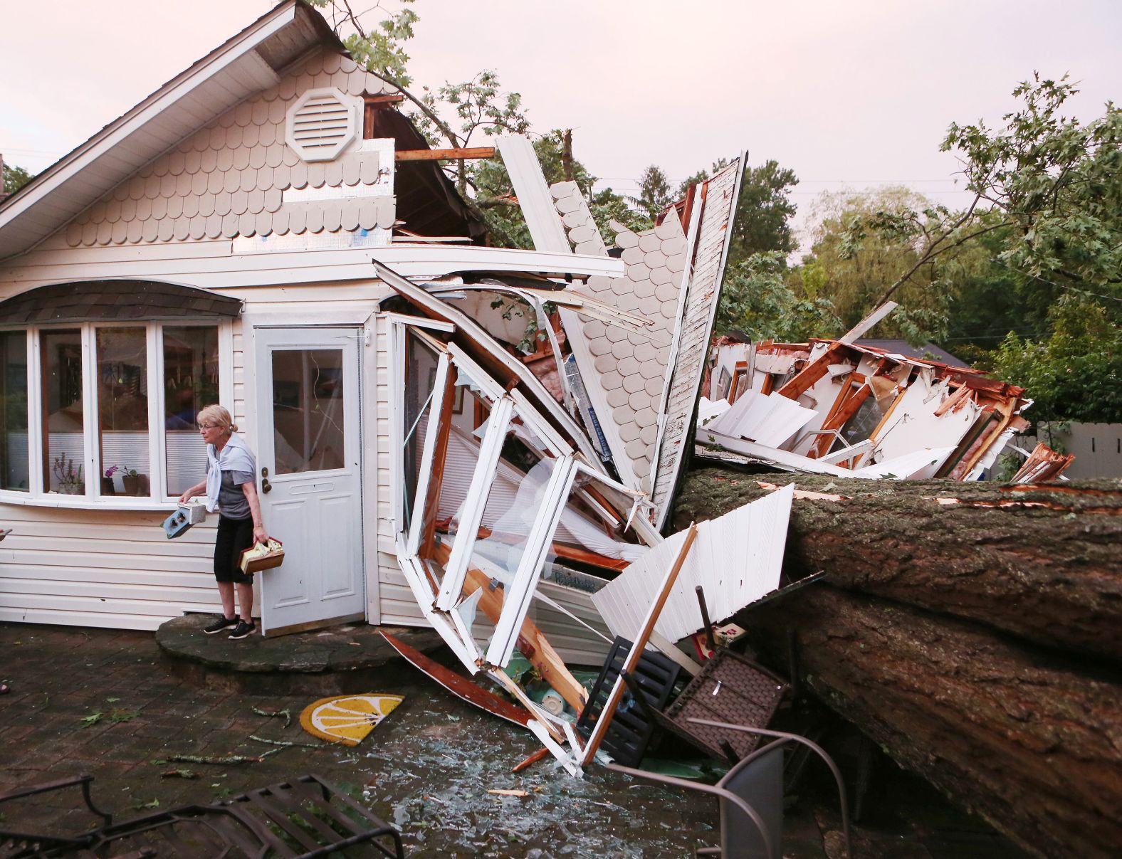 Joan Visbal leaves her home in North Salem, New York, after retrieving a few personal items on Sunday, June 23. A large tree, downed by a powerful storm, crushed half of the house while she was in it.