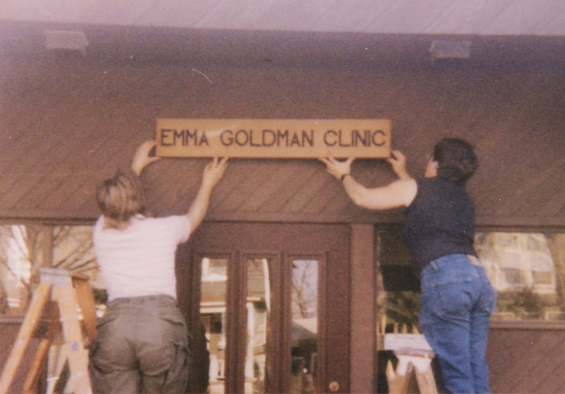 Two women hang a sign above the entrance of the Emma Goldman Clinic upon opening.