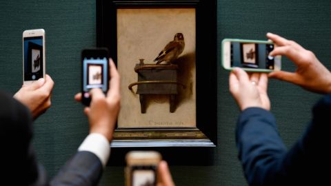 Gallery staff take photos on their phones of the painting by Carel Fabritius 'The Goldfinch' at the Scottish National Gallery on November 3, 2016. 