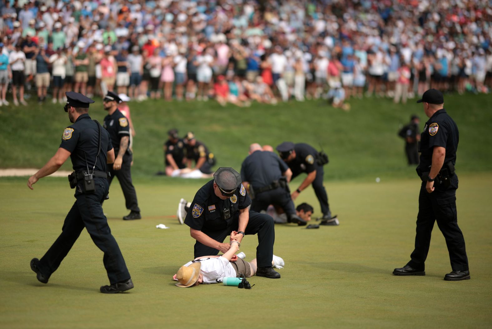 Climate protesters are detained by police on the 18th green after <a href="https://www.cnn.com/2024/06/23/sport/protesters-disrupt-travelers-championship/index.html">they interrupted the final round of the PGA Tour’s Travelers Championship</a> in Cromwell, Connecticut, on Sunday, June 23. The protesters left a powdery substance on the putting surface and delayed play for several minutes.