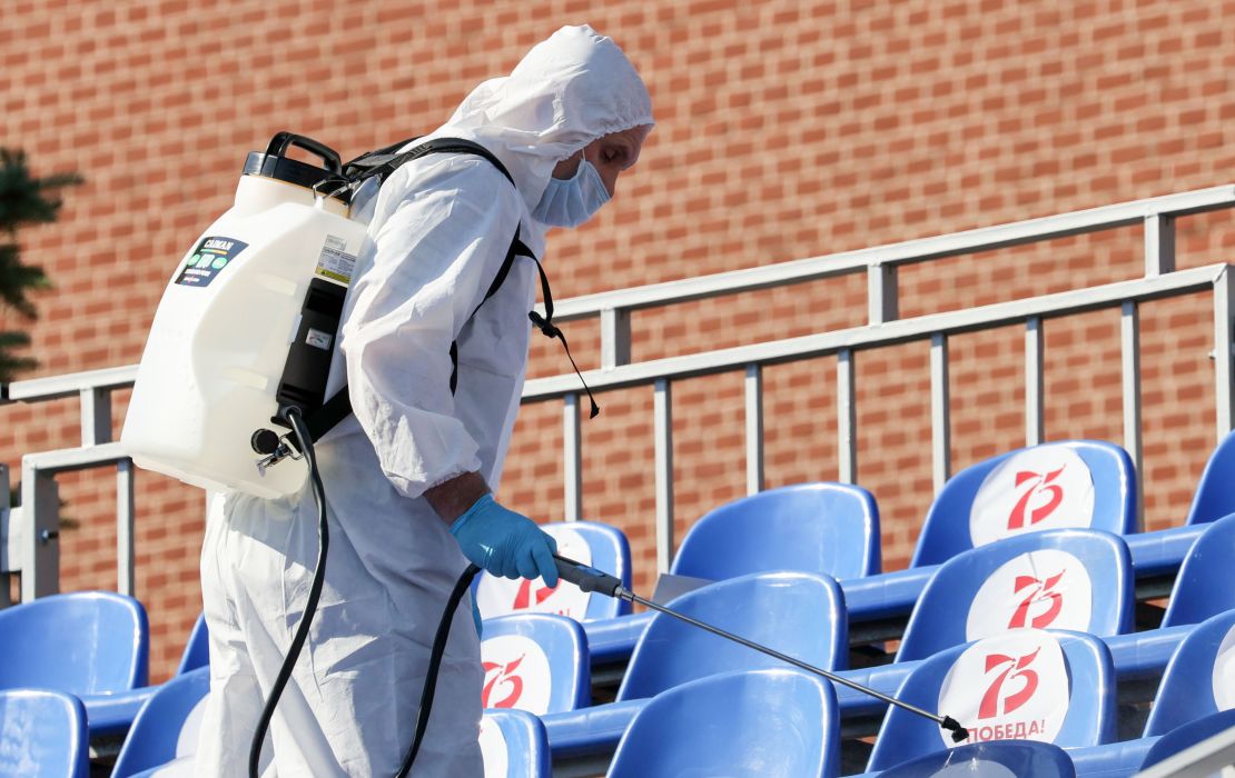 A sanitary worker in protective gear sprays disinfectant on seats in Red Square before the parade.