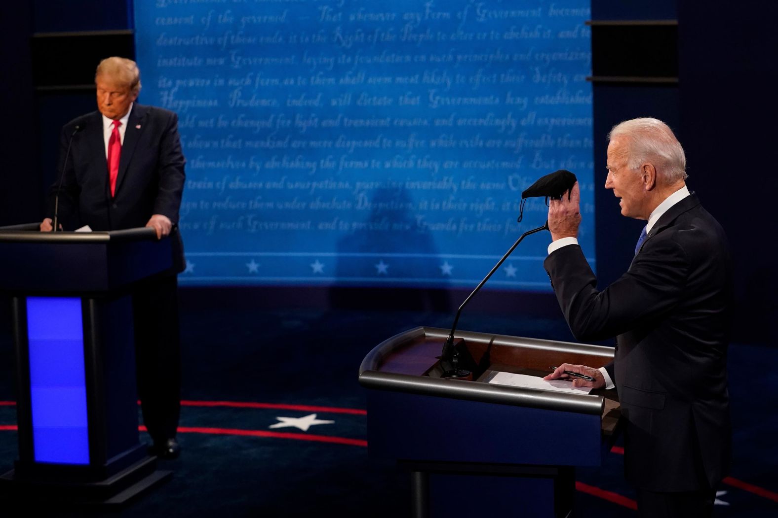 Biden holds up a mask as Trump takes notes during the debate section about Covid-19.