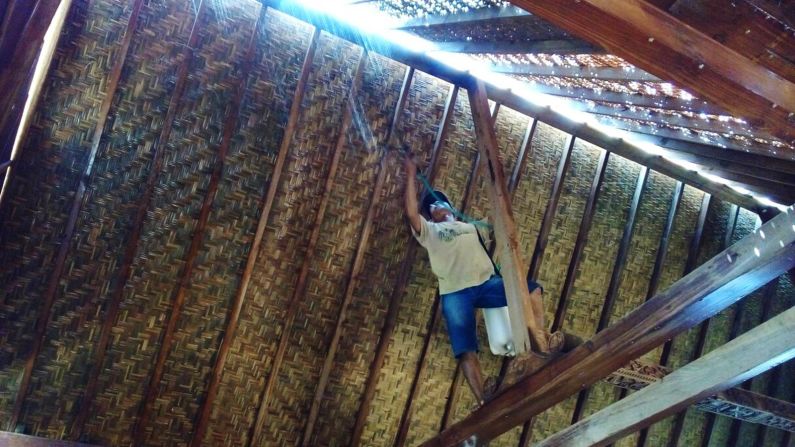 <strong>Protecting against the elements:</strong> A tukang (artisan) mold-proofs the bedek (traditional rattan-thatch ceiling). Once the house was ready, an indoor toilet was added, and Denham began moving in furniture, bookcases and antique trunks.  