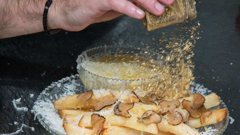 Chef Frederick Schoen-Kiewert applies 23-carat edible gold dust on top. as he prepares The Creme de la Creme Pommes Frites, the world's most expensive french fries, according to the Guinness Book of World Records, at Serendipity 3 restaurant New York City, New York, U.S., July 23, 2021. Picture taken July 23, 2021. REUTERS/Eduardo Munoz