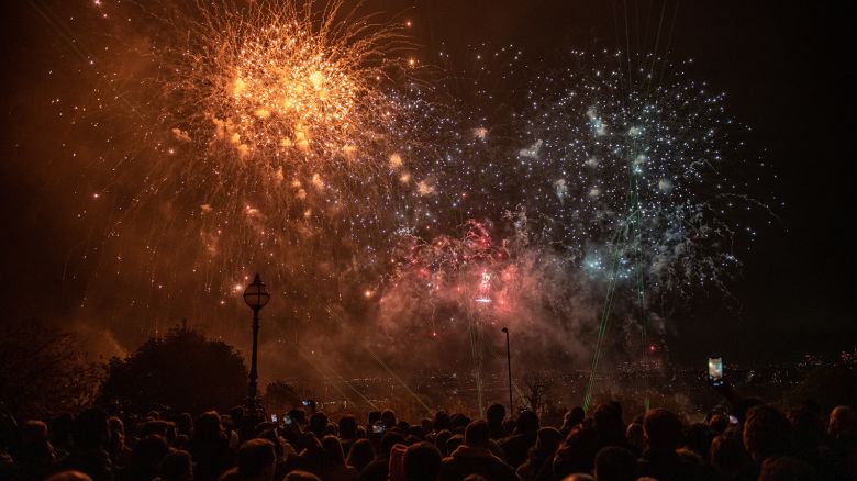 LONDON, ENGLAND - NOVEMBER 06: Crowds watch a firework display as part of bonfire night celebrations at Alexandra Palace with a view of the city of London in the distance on November 6, 2021 in London, England. In 1605, a group of persecuted Roman Catholic activists, including Guy Fawkes, attempted to to blow up the Palace of Westminster and assassinate the Protestant English King James I. Over 400 years later, people across the United Kingdom gather around bonfires and watch fireworks displays to mark the failure of the plot. (Photo by Chris J Ratcliffe/Getty Images)