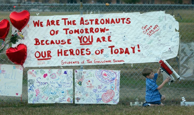 Averi Forline, 4, plays with a model of a space shuttle as he visits a growing memorial outside the main gate of Johnson Space Center in Houston on February 3, 2003. The memorial was created by NASA workers and other Houstonians in honor of the STS-107 crew.