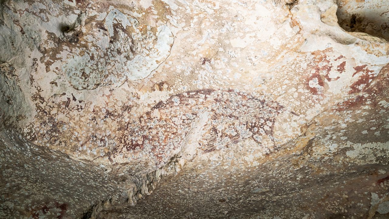 The scene, covered with calcium carbonate deposits, shows three human figures<strong> </strong>and a pig.