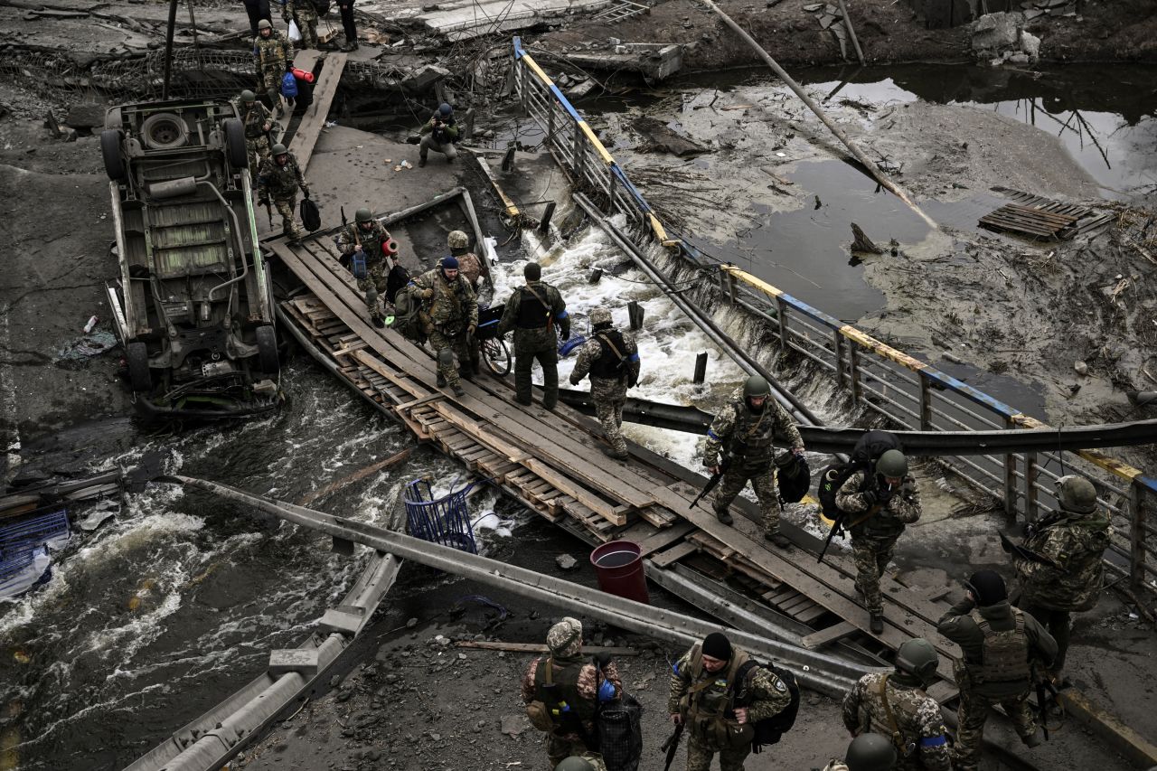 Ukrainian servicemen cross a makeshift path next to a destroyed bridge in Irpin, Ukraine on March 13. 