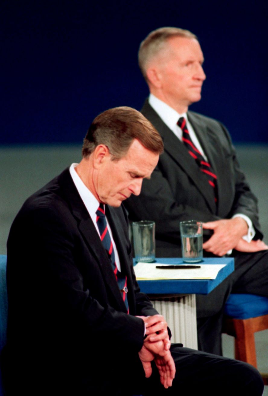 Bush looks at his watch during a town hall-style debate with Ross Perot, right, and Bill Clinton in 1992. It became a memorable footnote in his loss to Clinton later that year. Where Clinton was engaged with the audience, <a href="https://www.cnn.com/2012/10/02/politics/debate-moments-that-mattered/index.html">Bush appeared ready to check out</a>.