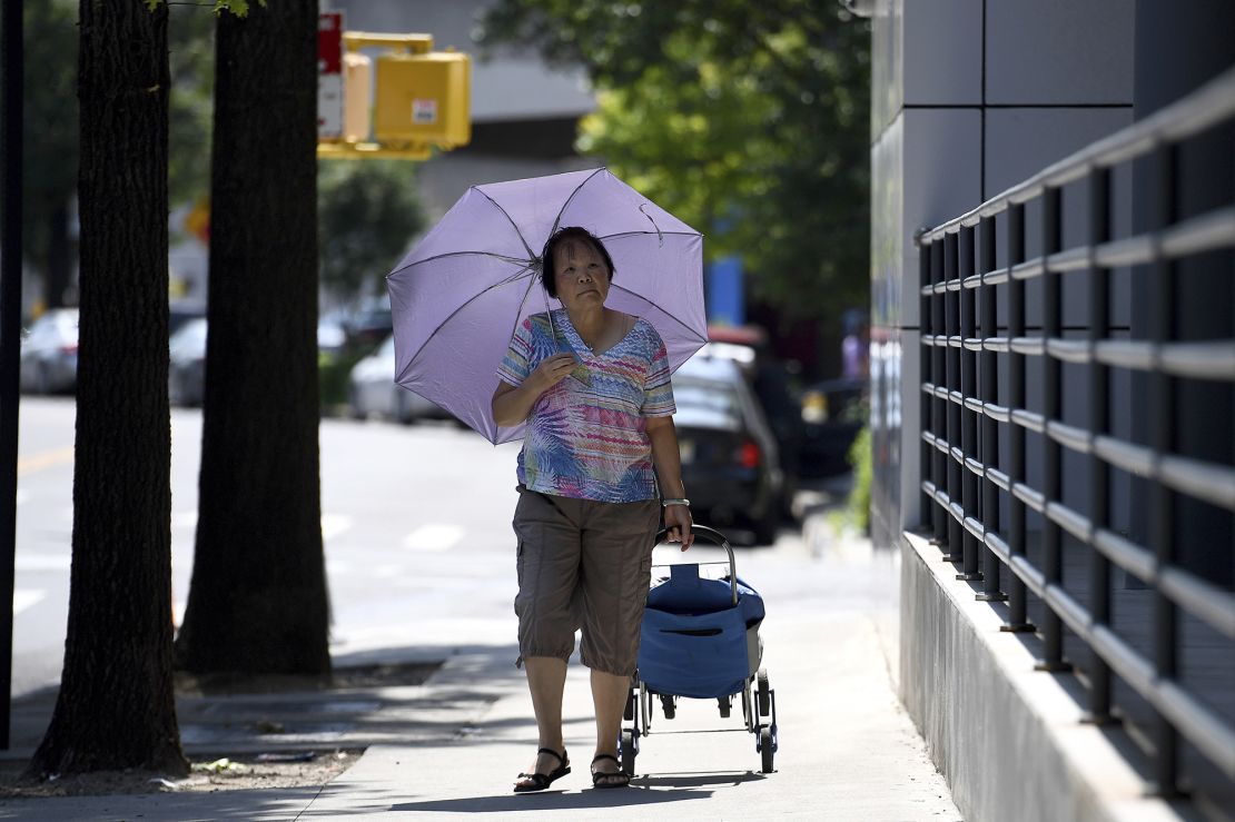 A woman uses an umbrella to shade herself from the sun in the Queens borough of New York City, NY, June 18, 2024. The city is under an extreme heat alert.