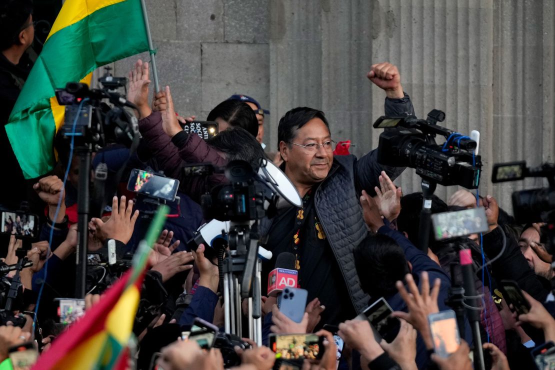 Bolivian President Luis Arce raises a clenched fist, surrounded by supporters and media, outside the government palace in La Paz, Bolivia, on June 26, 2024.