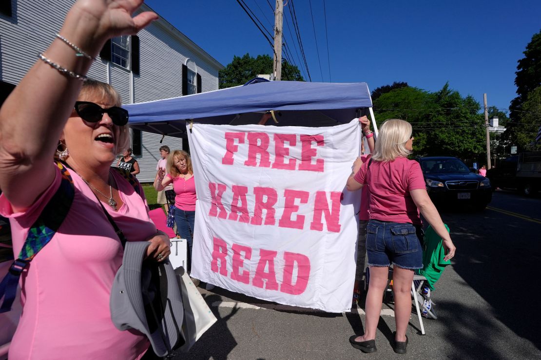 Eva Jenkins waves to passing cars as other supporters place a "Free Karen Read" banner a block away from Norfolk Superior Court on Tuesday in Dedham, Massachusetts.