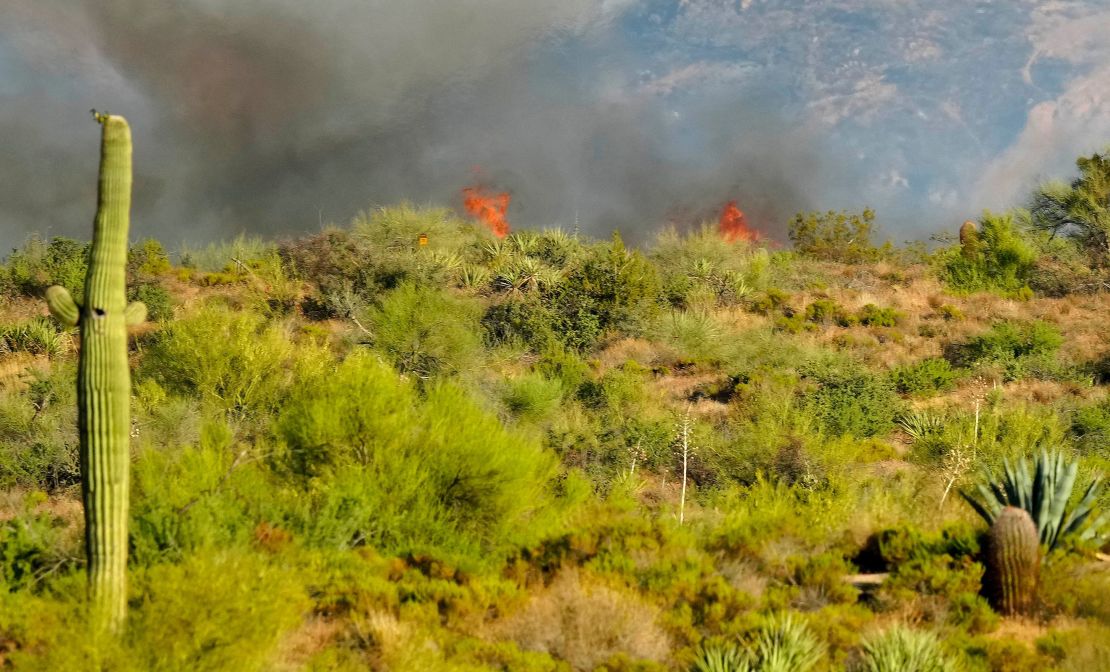 Fire peaks over a hill as smoke emerges from the Boulder View fire in North Scottsdale, Arizona, on Friday, June 28. 