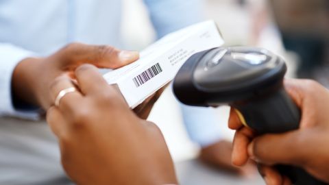 Closeup shot of a pharmacist scanning a box of medication for a customer in a chemist