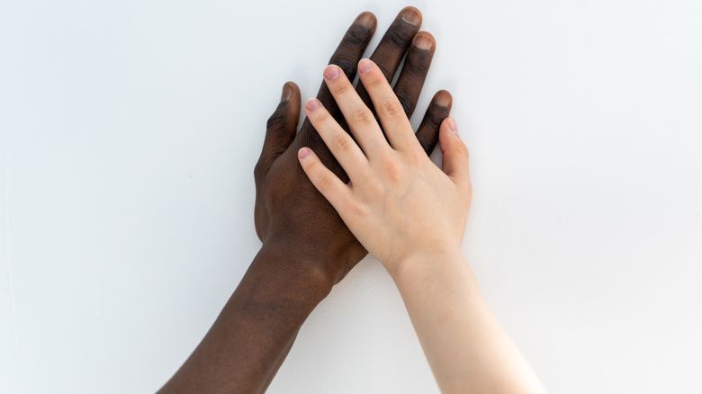 Two hands, black and white, united on white background. Love and strength power