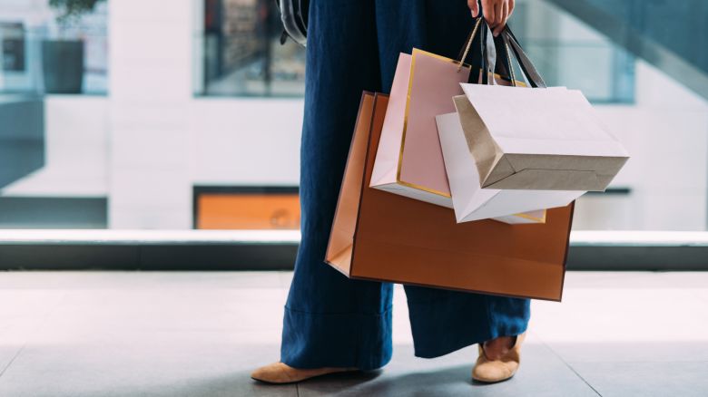 An unrecognizable woman standing at the shopping mall with bags.