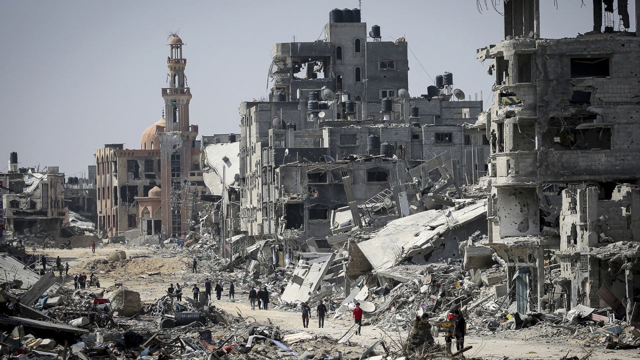 People walk amid the rubble of buildings destroyed during Israeli bombardment in Khan Younis, in southern Gaza, on April 16, 2024.