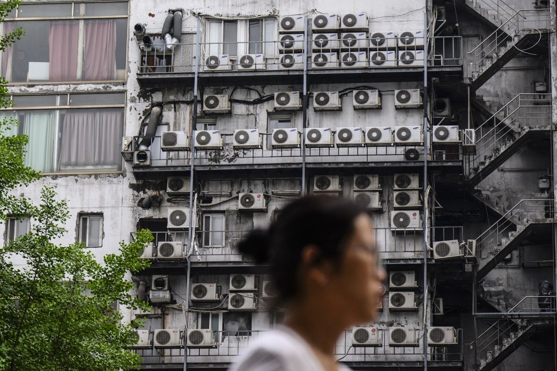 A woman walks past air-conditioning units outside a building in Seoul on April 30, 2024.