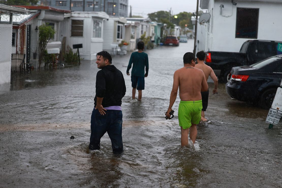 People walk through a flooded street on Wednesday in Hallandale Beach, Florida.