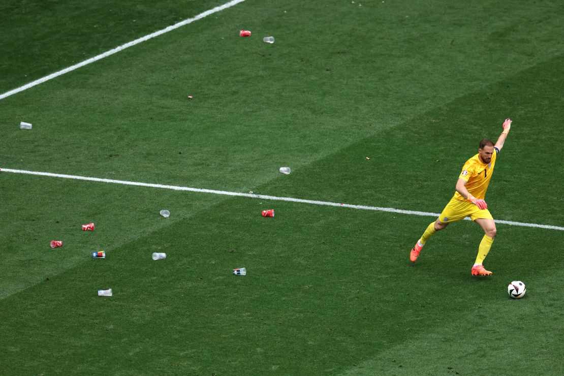 Slovenia goalkeeper Jan Oblak takes a freekick during a game against Serbia at Euro 2024 with beer cups around him.