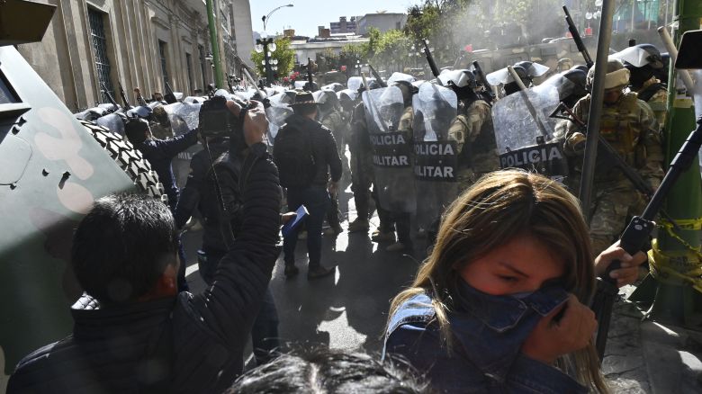 TOPSHOT - A woman walks away from tear gas fired by military troops outside the Quemado Palace at Plaza Murillo in La Paz on June 26, 2024.