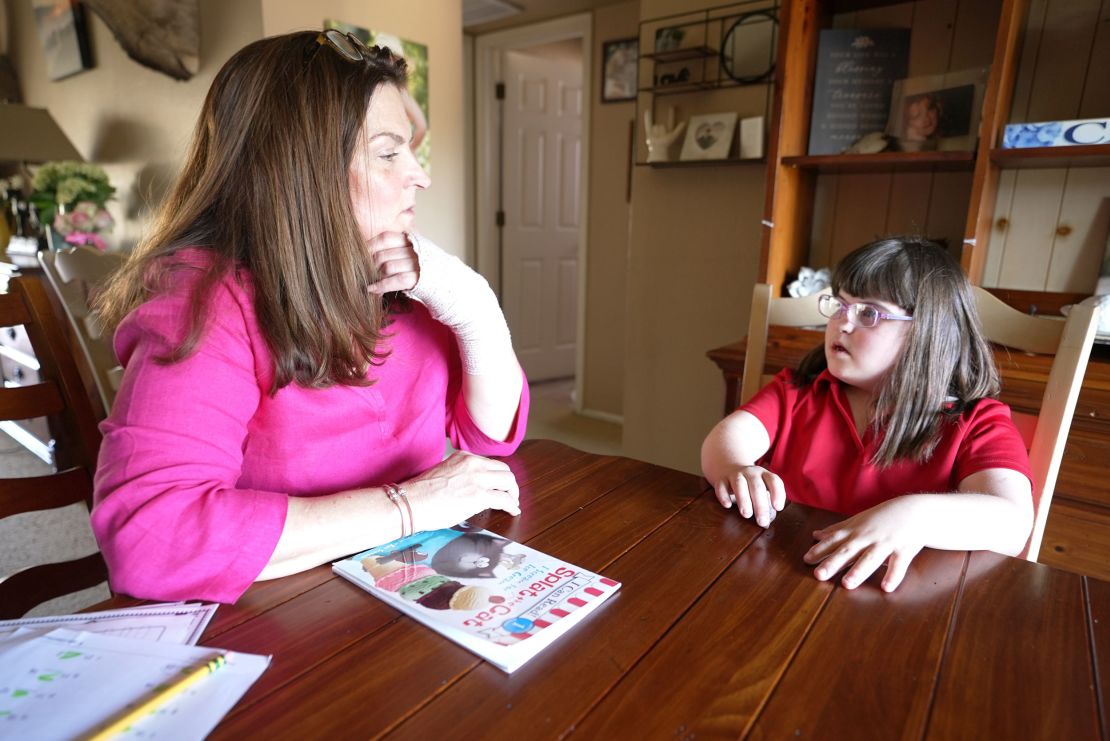 Felicia White helps her daughter Riley, a student at an Arizona public school that shut down last month, with her homework.