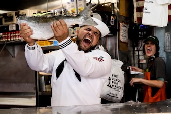 GSEFN Jaxon Moon assigned to USS Sampson (DDG 102), celebrates catching a fish at Pike Place Market in Seattle.