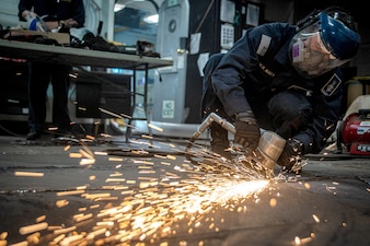 AM3 Sterling Smith grinds deckplates aboard USS Nimitz (CVN 68) in the Pacific Ocean.