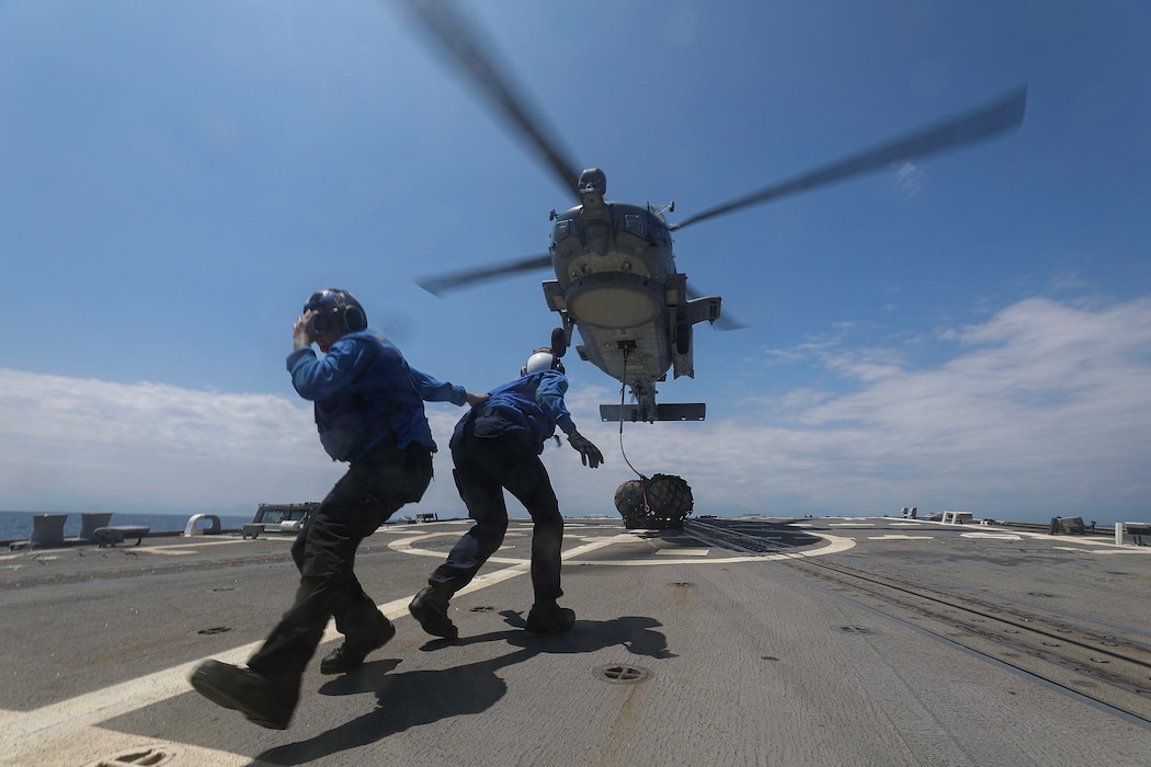 Sailors clear the flight deck aboard USS Dewey (DDG 105) after attaching a training pallet to an MH-60R Sea Hawk helicopter from HSM-51 during vertical replenishment training in the Philippine Sea.