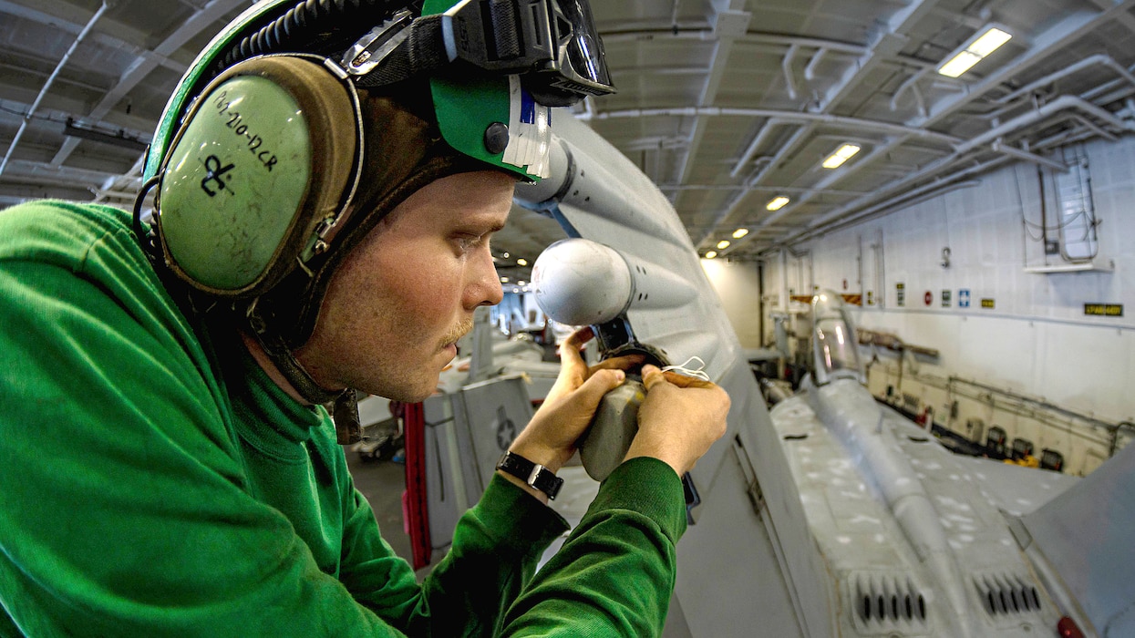 A Sailor maintains an EA-18G Growler from VAQ-137 in the hangar bay aboard USS Theodore Roosevelt (CVN 71) in the U.S. 5th Fleet area of operations.