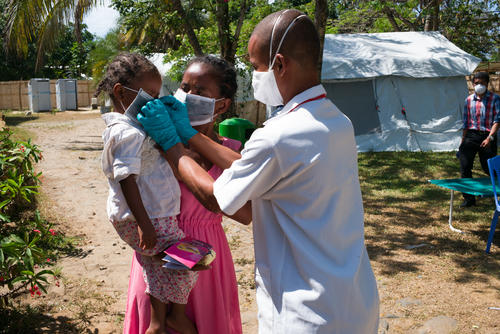  A Doctor in the care center for patients infected with plague helps a little girl put on her protective mask.