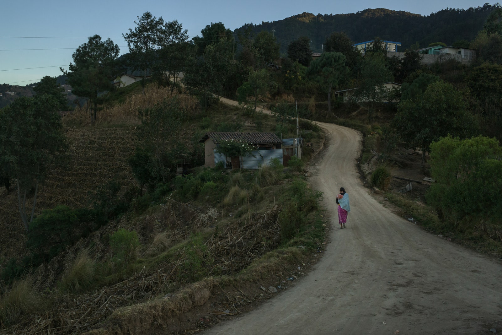 At dusk a mother walks back home with her baby.