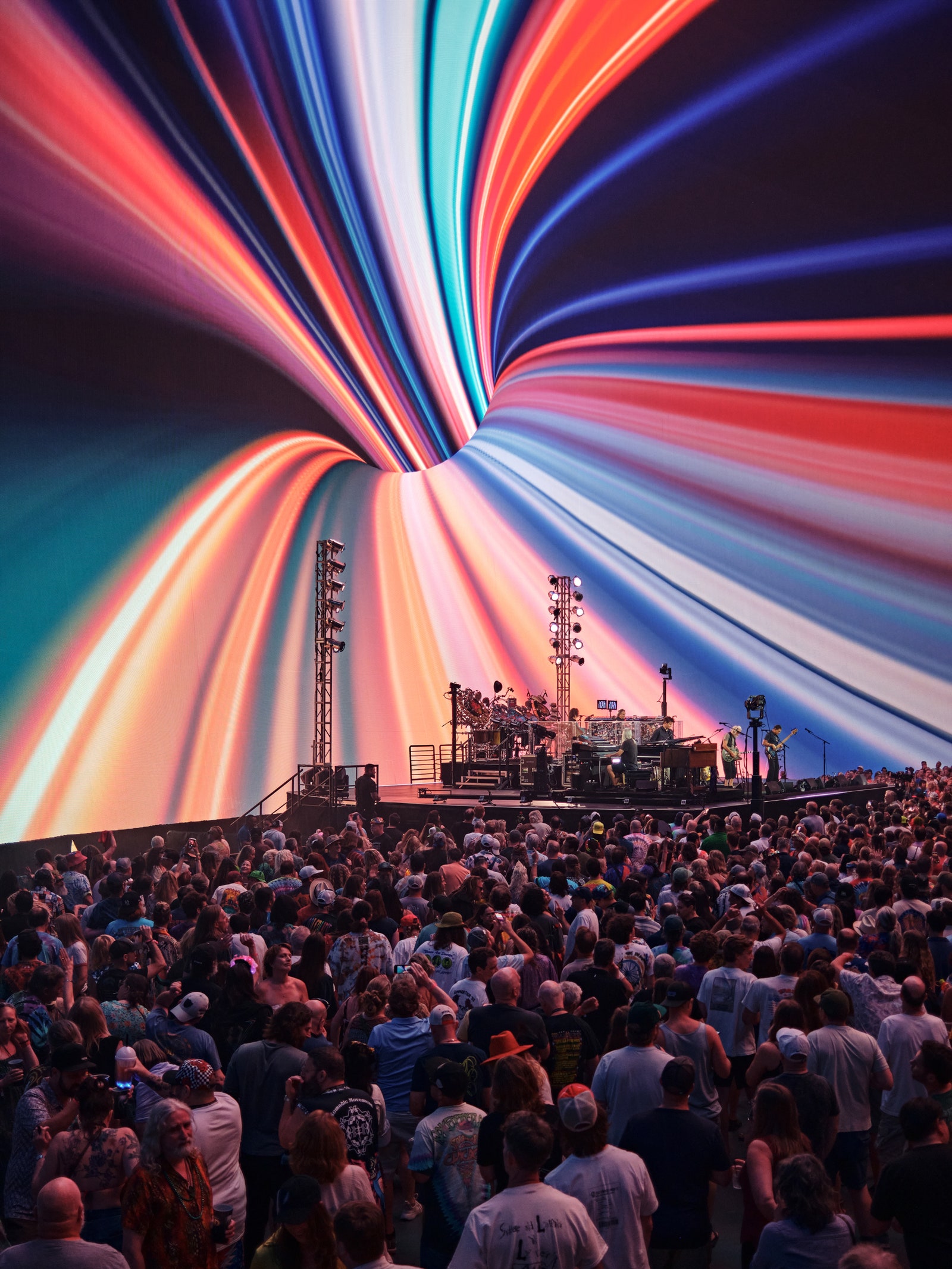 A photograph from inside The Sphere that features a crowd standing before a big screen and a band.