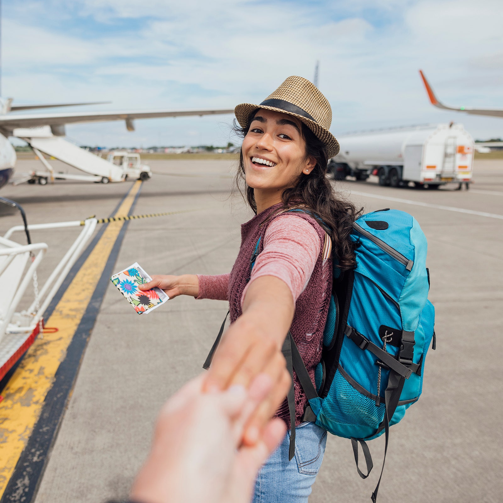 A woman holding someones hand while walking toward a small plane.