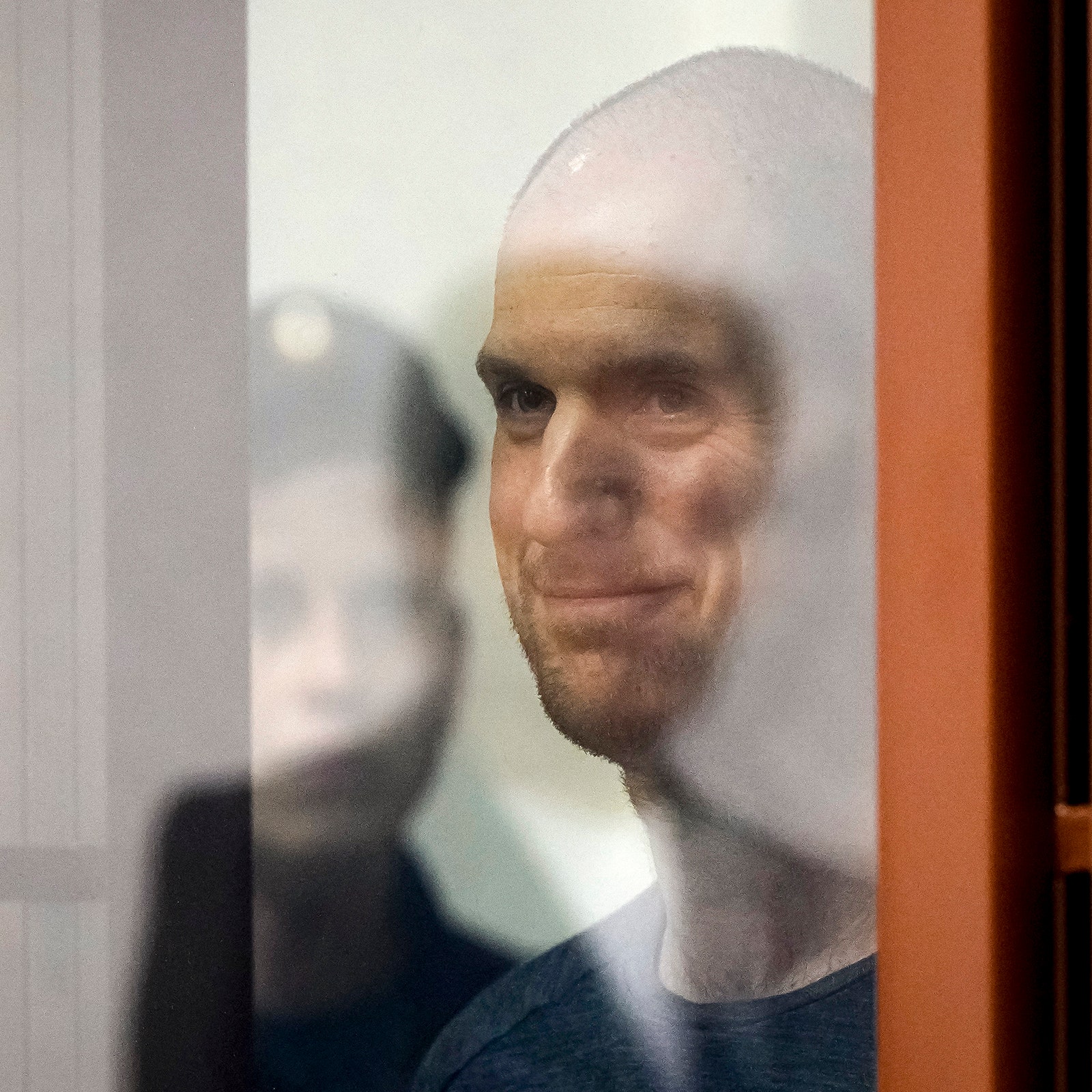 A photo of the Wall Street Journal reporter Evan Gershkovich pictured through a glass window of a courtroom in Russia in...