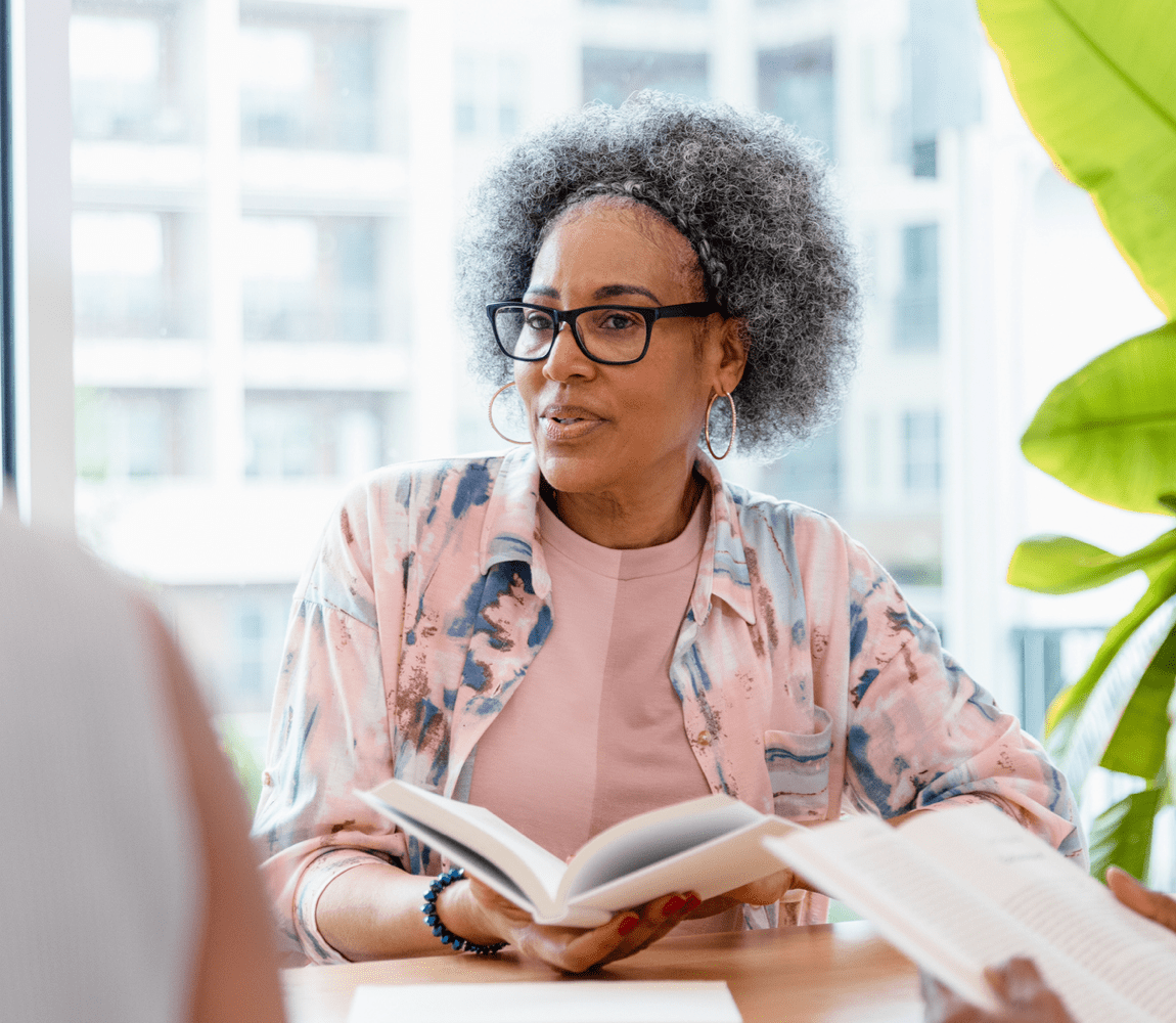 Woman at table holding open book