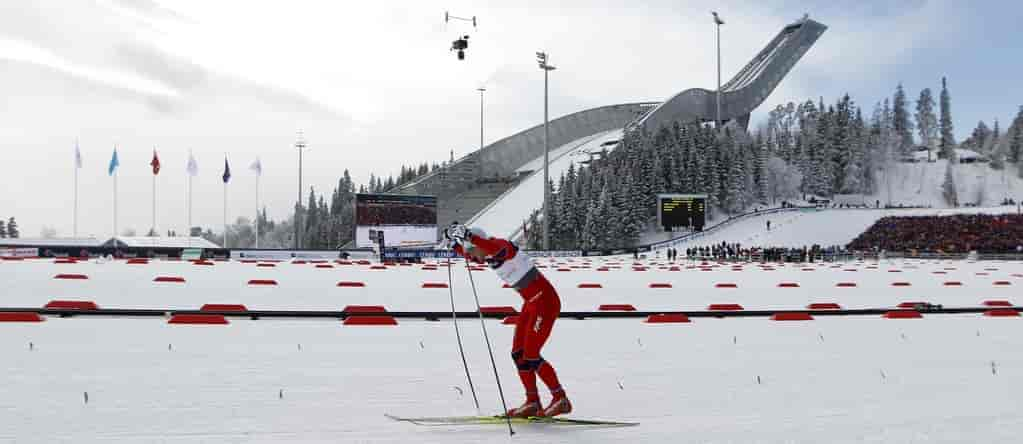 Northug skøyter på langrennsski med Holmenkollbakken i bakgrunnen.