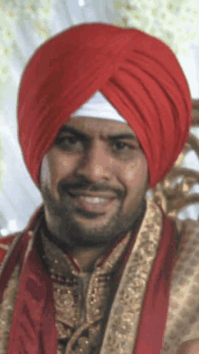 a man is wearing a red turban and smiling for the camera