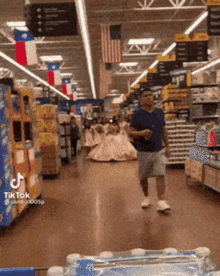 a man in a blue shirt is walking through a store with a woman in a wedding dress behind him