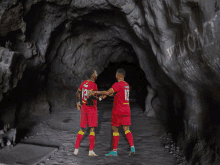 two soccer players shaking hands in a cave with a sign that says welcome