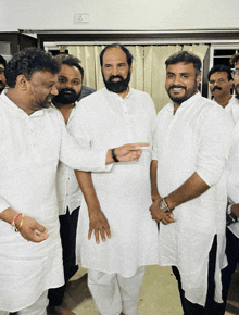 a group of men in white shirts are standing together