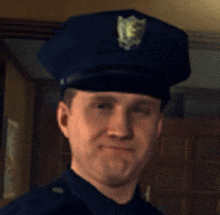 a man in a police uniform is smiling and wearing a hat with a shield on it .