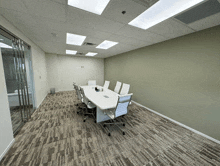 a conference room with white chairs and a long white table