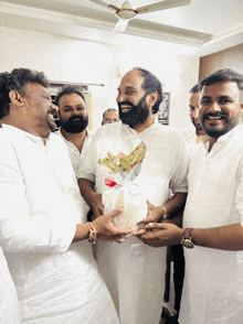 a group of men are posing for a picture and one of them is holding a bouquet of flowers